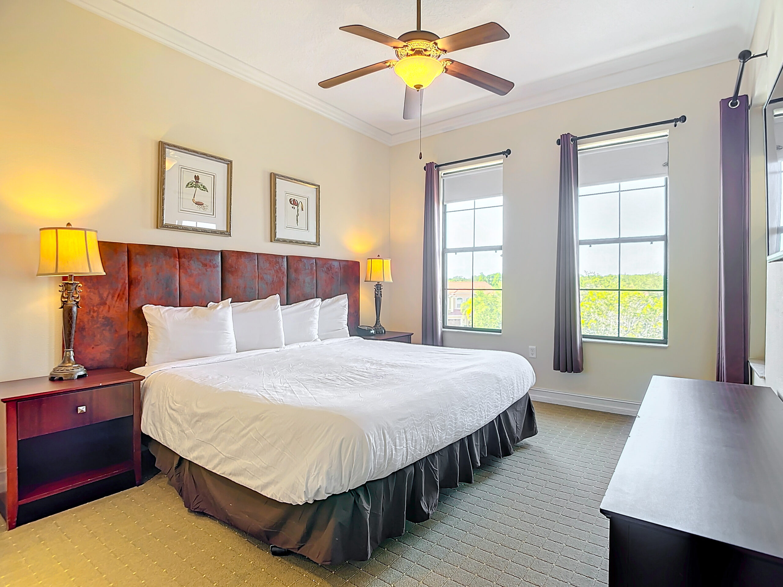 Cozy bedroom with a large bed, ceiling fan, and framed wall art.